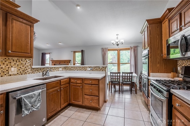 kitchen with a chandelier, kitchen peninsula, sink, appliances with stainless steel finishes, and light tile patterned flooring