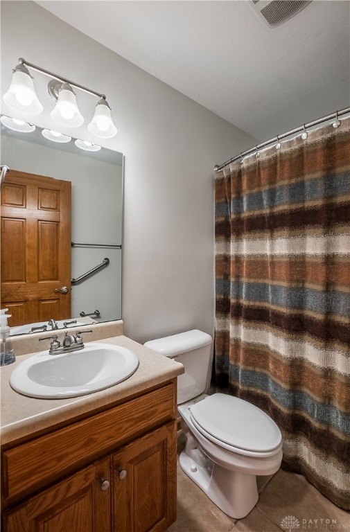 bathroom featuring tile patterned flooring, vanity, toilet, and curtained shower