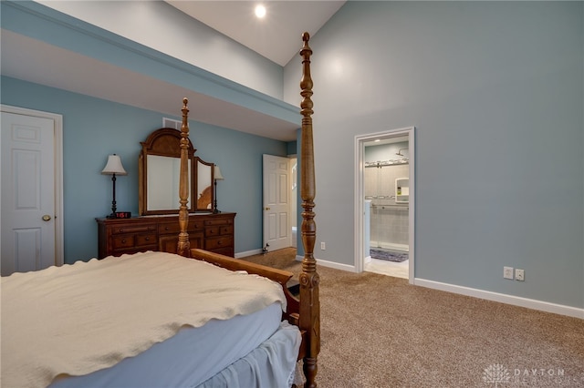 carpeted bedroom featuring ensuite bath and high vaulted ceiling