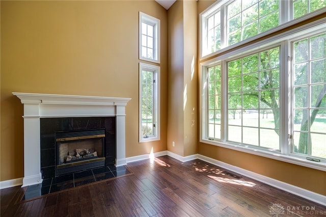 unfurnished living room featuring dark hardwood / wood-style flooring and a tile fireplace