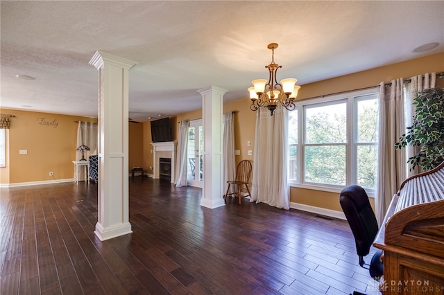 office with ornate columns, dark wood-type flooring, a textured ceiling, and an inviting chandelier