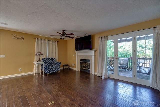 living area featuring ceiling fan, a textured ceiling, a fireplace, and dark hardwood / wood-style flooring