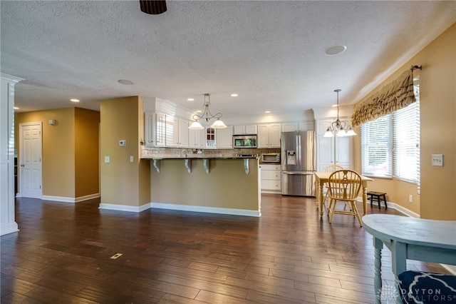 kitchen with stainless steel appliances, decorative light fixtures, a kitchen bar, and white cabinets