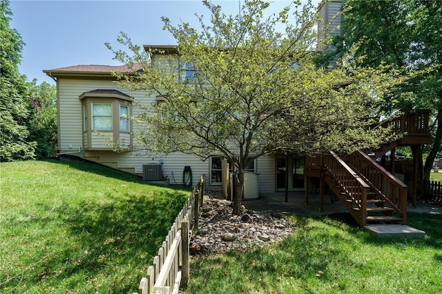 back of house with central AC unit, a yard, and a deck