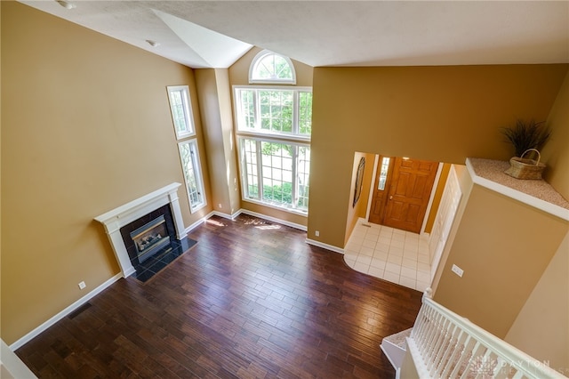 living room featuring lofted ceiling, dark hardwood / wood-style flooring, and a tiled fireplace