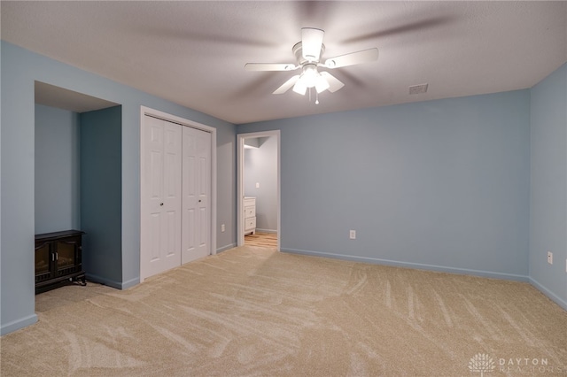 unfurnished bedroom with light carpet, a closet, and ceiling fan