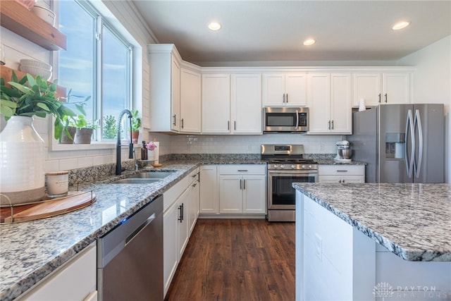 kitchen with appliances with stainless steel finishes, tasteful backsplash, dark wood-type flooring, sink, and white cabinets