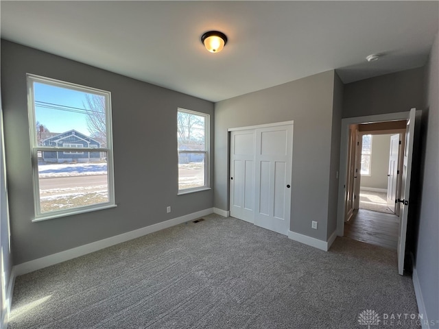 unfurnished bedroom featuring multiple windows, carpet, and a closet