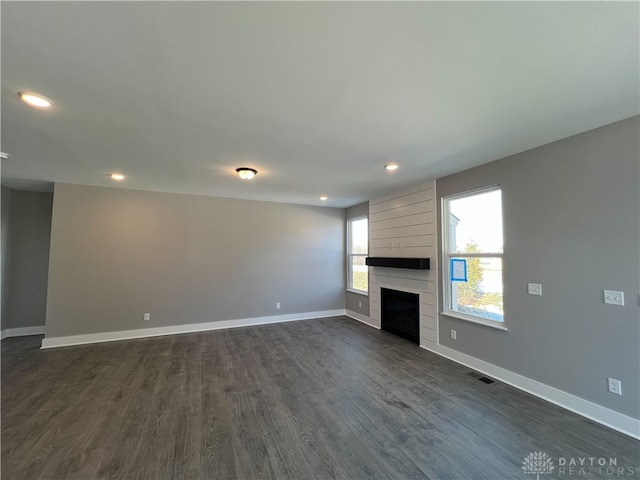 unfurnished living room featuring dark hardwood / wood-style floors and a large fireplace