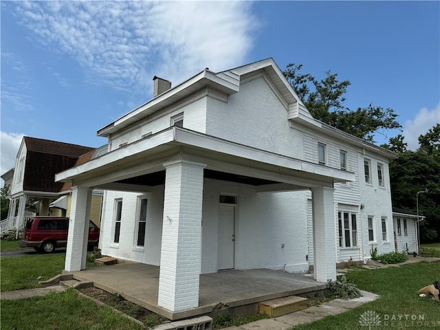 rear view of house featuring a lawn and a carport