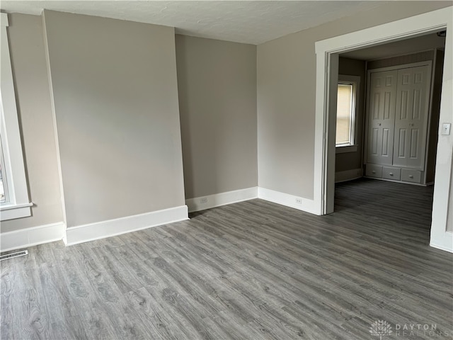 empty room featuring a textured ceiling and dark wood-type flooring