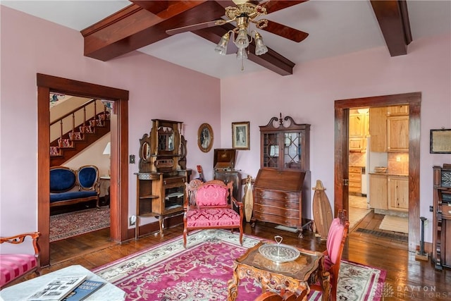 sitting room with ceiling fan, dark hardwood / wood-style flooring, and beamed ceiling