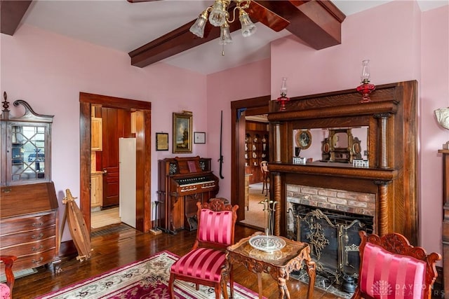 living room featuring ceiling fan, a fireplace, hardwood / wood-style floors, and beamed ceiling