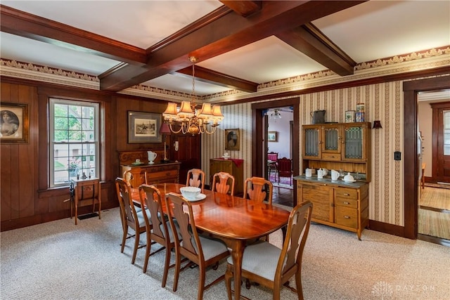 carpeted dining space featuring an inviting chandelier, ornamental molding, and beamed ceiling