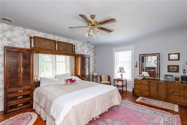 bedroom featuring ceiling fan, dark wood-type flooring, and multiple windows