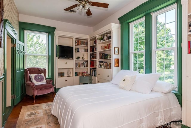 bedroom with ceiling fan, multiple windows, and hardwood / wood-style flooring