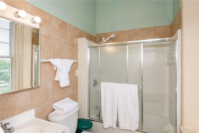 full bathroom featuring enclosed tub / shower combo, sink, tile walls, and toilet