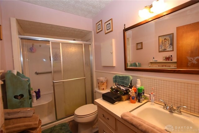 bathroom featuring a textured ceiling, an enclosed shower, vanity, and toilet