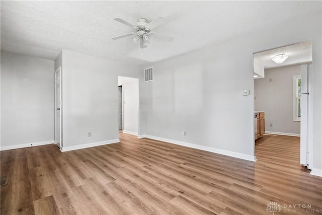 empty room with ceiling fan, light hardwood / wood-style flooring, and a textured ceiling