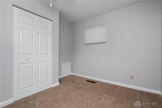 unfurnished bedroom featuring carpet floors, a closet, and a textured ceiling