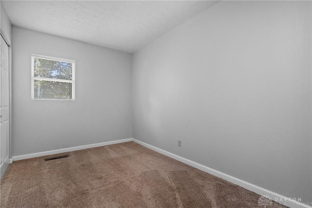 empty room with a textured ceiling and carpet flooring