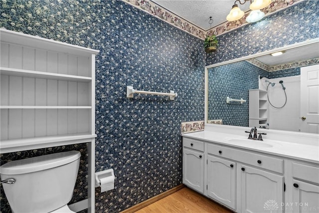 bathroom with hardwood / wood-style flooring, vanity, toilet, and a textured ceiling