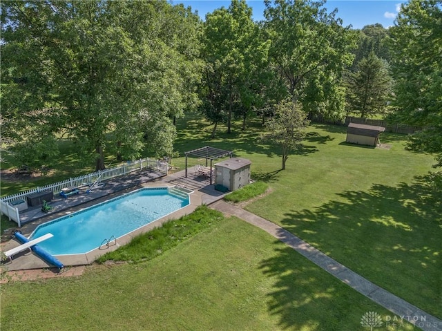 view of pool featuring a storage unit, a diving board, and a lawn