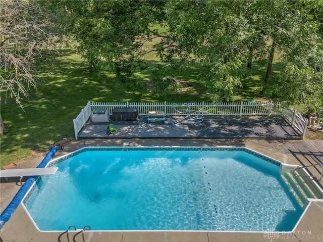 view of swimming pool featuring a wooden deck, a lawn, and a diving board