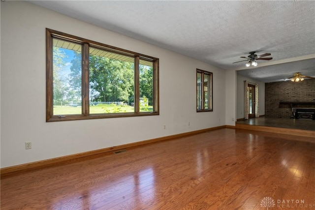 unfurnished living room featuring ceiling fan, hardwood / wood-style floors, and a textured ceiling