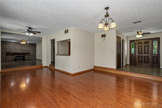 unfurnished living room with ceiling fan with notable chandelier, hardwood / wood-style floors, and a textured ceiling