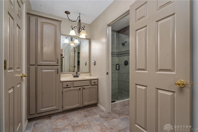 bathroom with vanity, a shower with door, and a textured ceiling