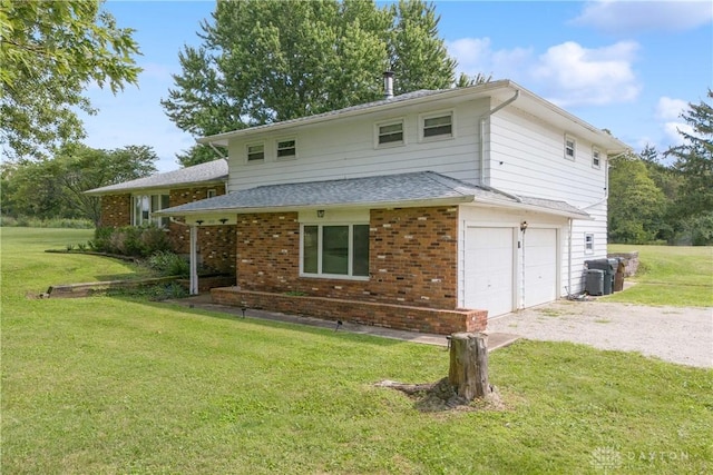 back of property featuring cooling unit, a garage, and a yard