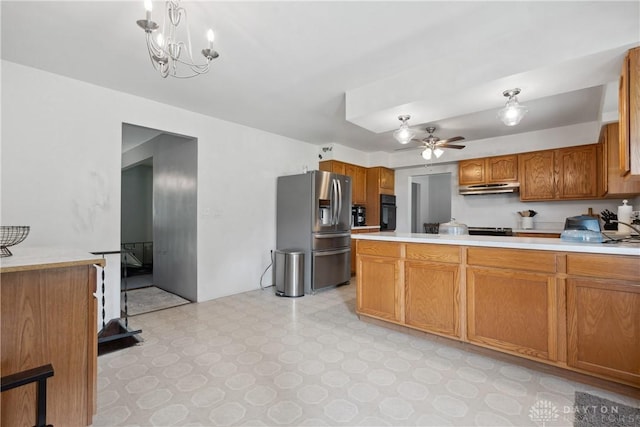 kitchen with stainless steel refrigerator with ice dispenser, stove, oven, decorative light fixtures, and ceiling fan with notable chandelier