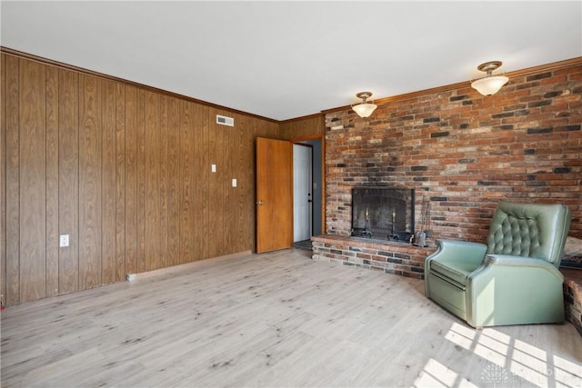 unfurnished living room with crown molding, wooden walls, a fireplace, and light hardwood / wood-style floors