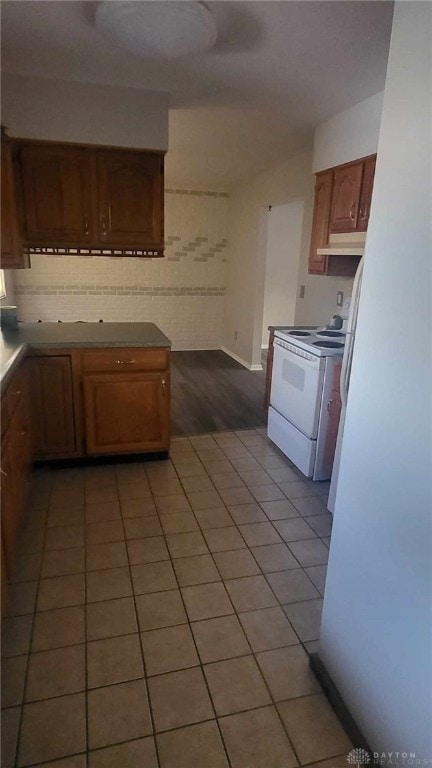 kitchen with light tile patterned flooring, white range with electric cooktop, and decorative backsplash