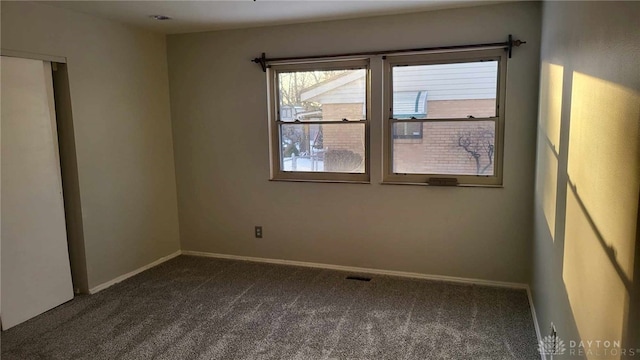 unfurnished room featuring dark colored carpet