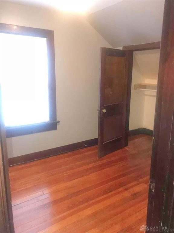 unfurnished bedroom featuring a closet, hardwood / wood-style flooring, and lofted ceiling