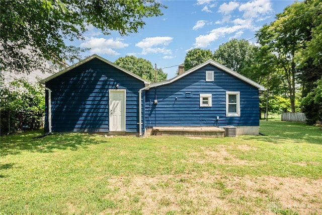 rear view of property featuring a yard and central air condition unit