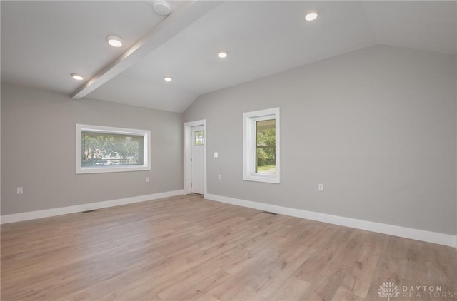 empty room featuring light wood-type flooring and vaulted ceiling with beams