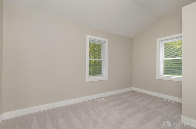 carpeted spare room with lofted ceiling