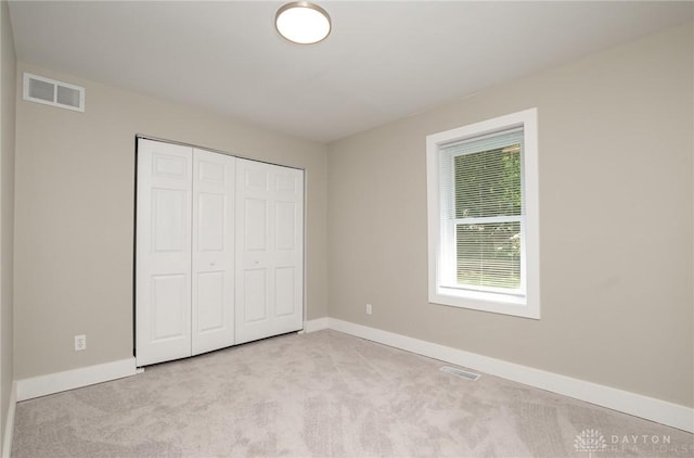 unfurnished bedroom featuring light carpet and a closet