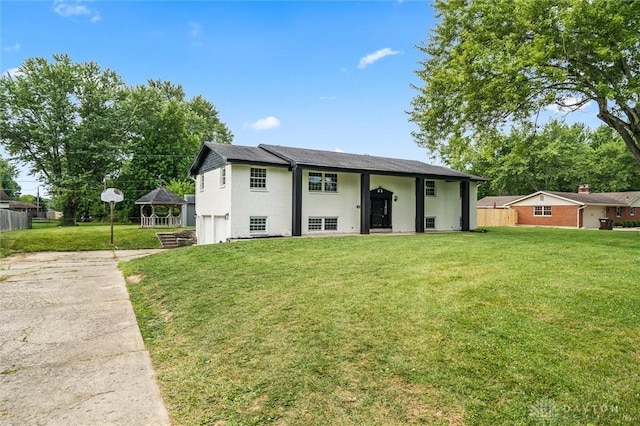 exterior space with stucco siding, concrete driveway, a lawn, an attached garage, and fence