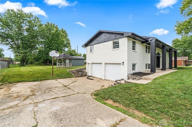 view of side of property featuring driveway, brick siding, a lawn, and an attached garage