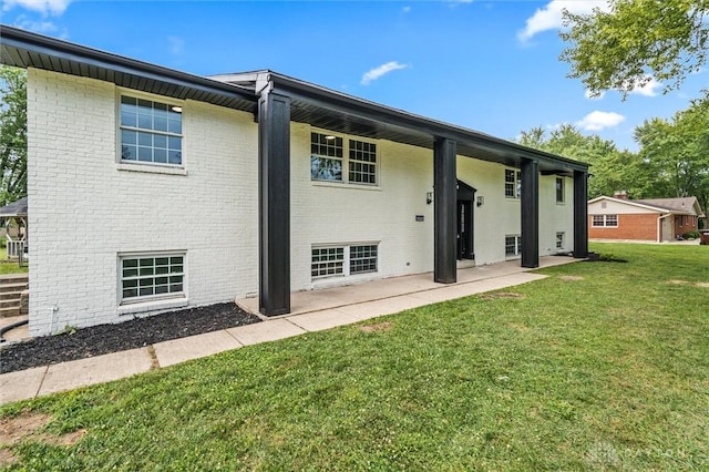 back of house featuring a yard, brick siding, and a patio