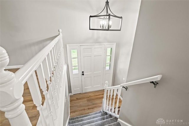 entrance foyer featuring baseboards, stairway, a chandelier, and wood finished floors