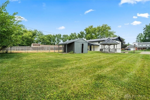 view of yard featuring an outbuilding, a gazebo, and fence