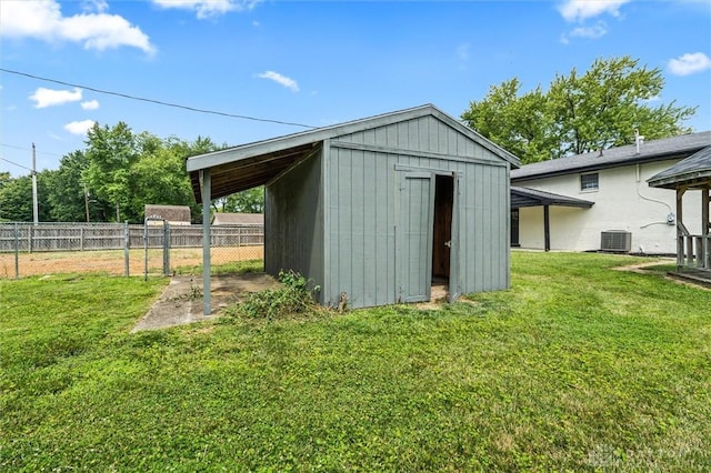 view of shed with a carport, cooling unit, and fence