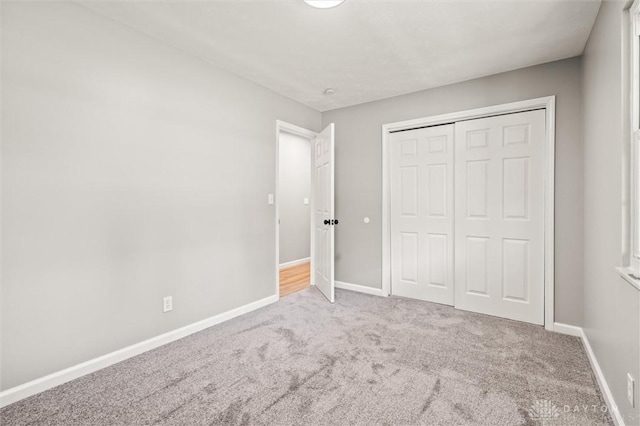 unfurnished bedroom with carpet floors, a closet, and baseboards