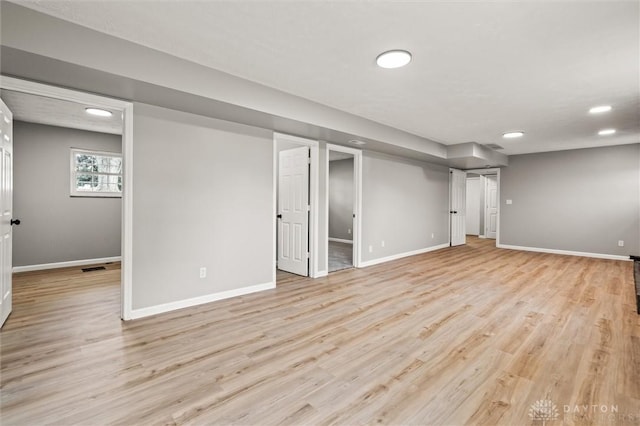 basement with light wood finished floors, visible vents, and baseboards