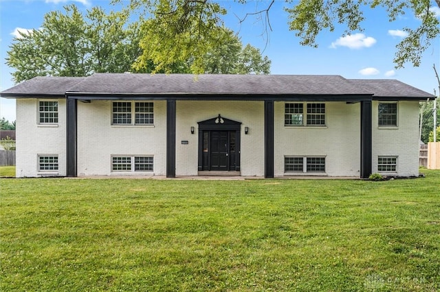 raised ranch featuring brick siding and a front yard